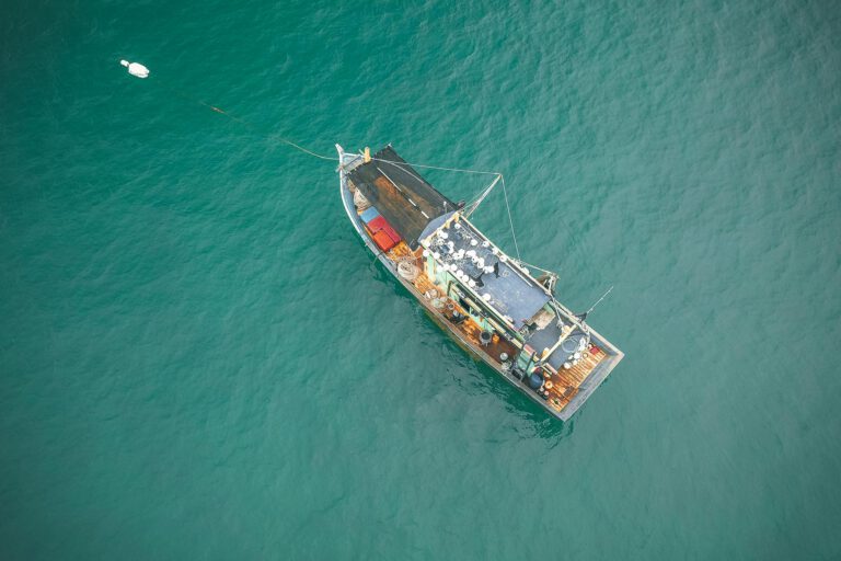 Drone view of big fishing vessel moored on rippling azure seawater on clear summer day