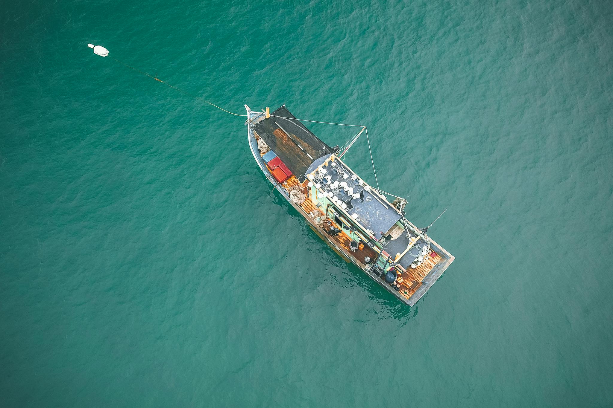 Drone view of big fishing vessel moored on rippling azure seawater on clear summer day